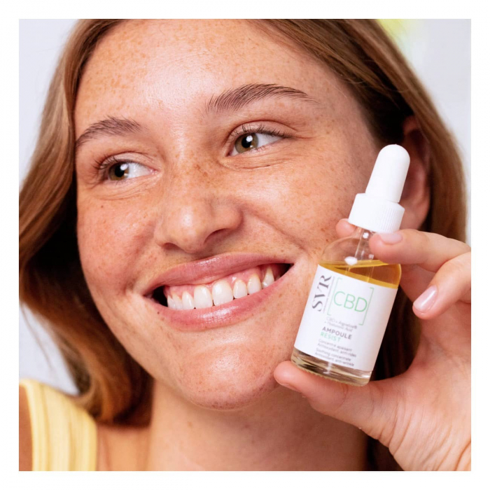 A woman with rosacea holding a rosacea serum